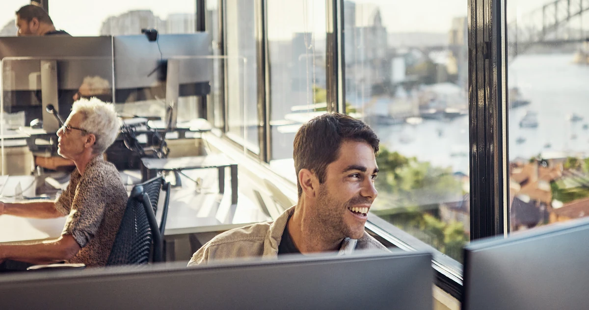 Two colleagues at their desks in an office with a harbour view