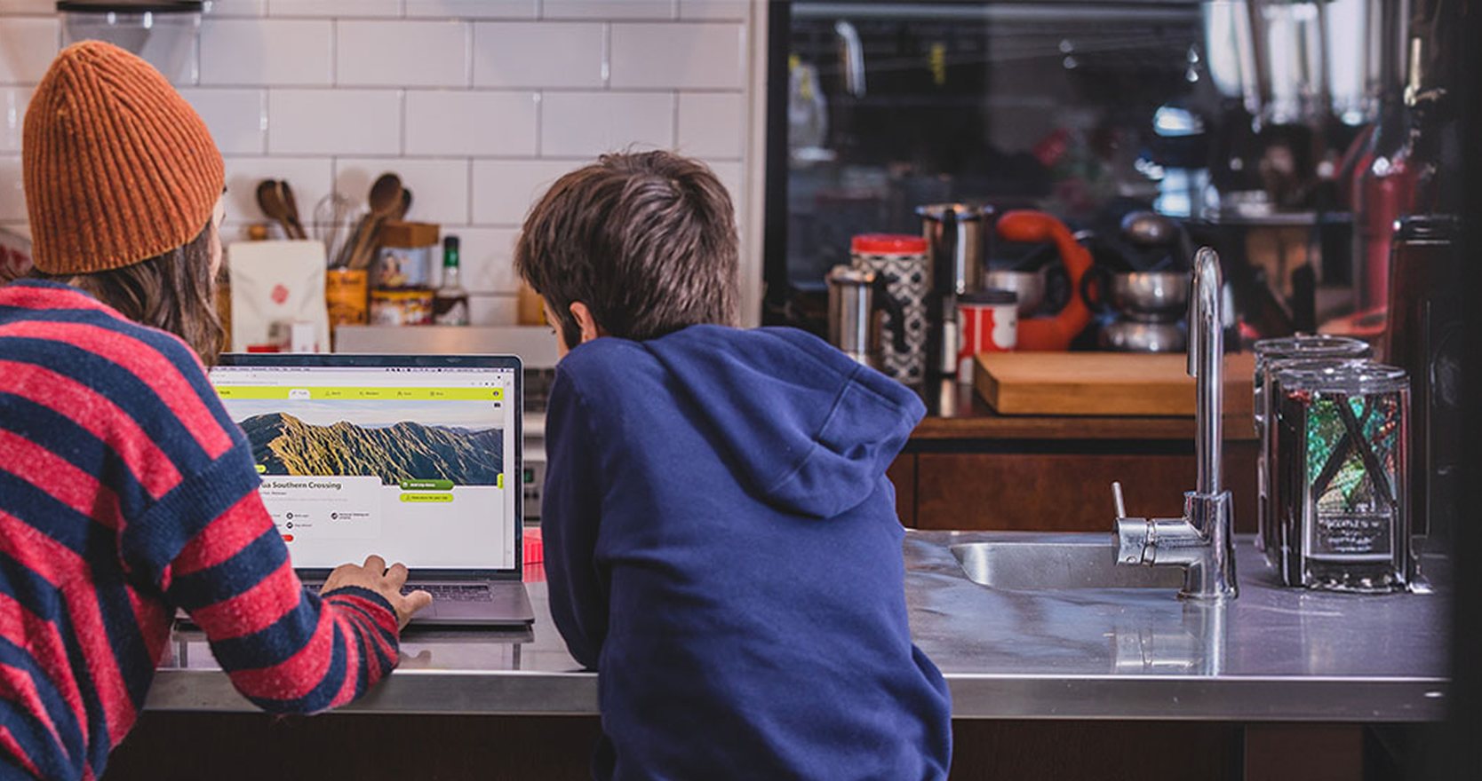 A woman and a boy at a kitchen bench looking at a track page on the Plan My Walk website